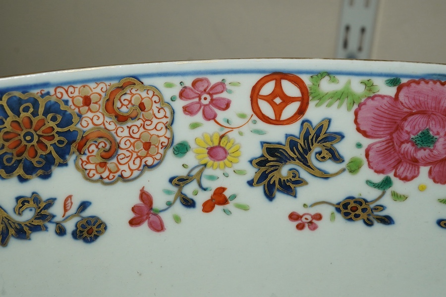 A large Chinese famille rose punch bowl, Qianlong period, the exterior painted with flowers in a fenced garden, the interior with a flower bouquet within a garland of flowers, 40.5cm diameter, wood stand. Condition - som